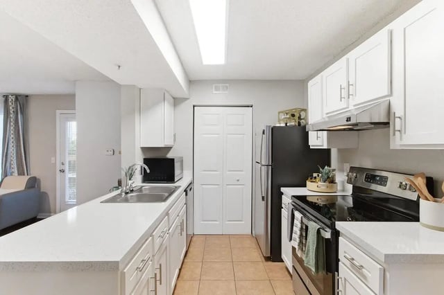 White cabinets stainless steel appliances and sink kitchen at ReNew Tallahassee in Tallahassee Student Accommodation