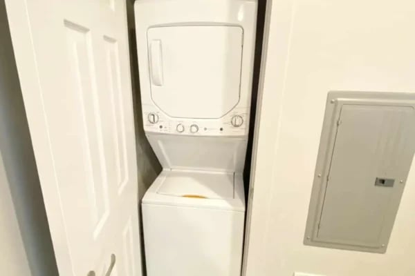 Stacked white washer dryer unit utility closet at The Factory Student Housing in Logan Student Accommodation
