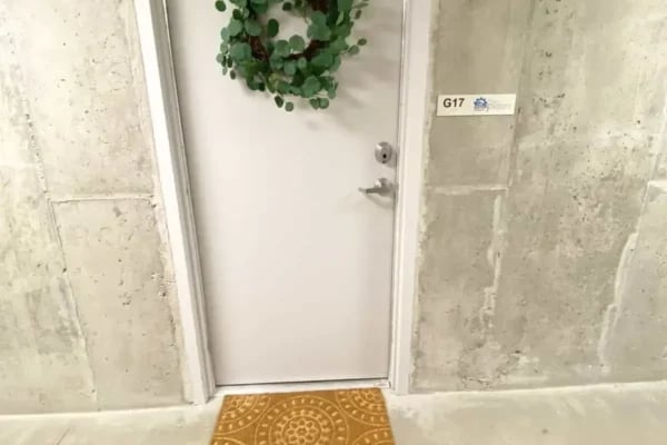 White door green wreath welcome mat exterior at The Factory Student Housing in Logan Student Accommodation