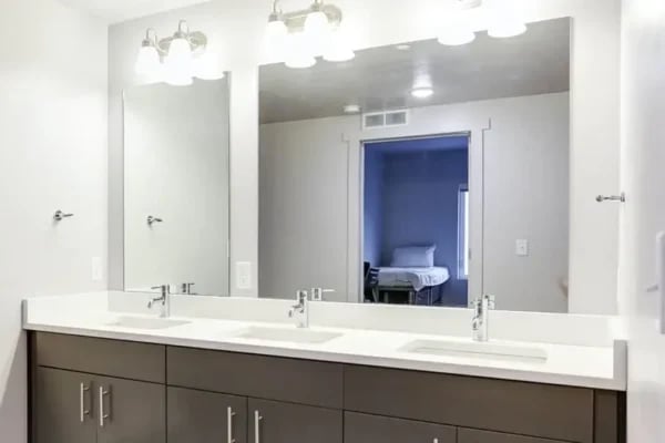 Triple vanity sinks with mirrors reflecting bedroom Bathroom at The Factory Student Housing in Logan Student Accommodation