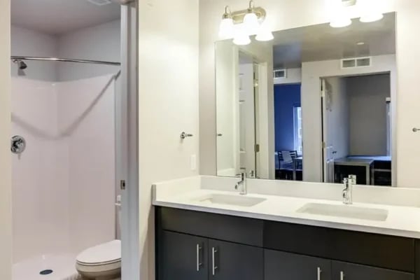 Shower toilet dual sinks dark vanity mirror bathroom at The Factory Student Housing in Logan Student Accommodation