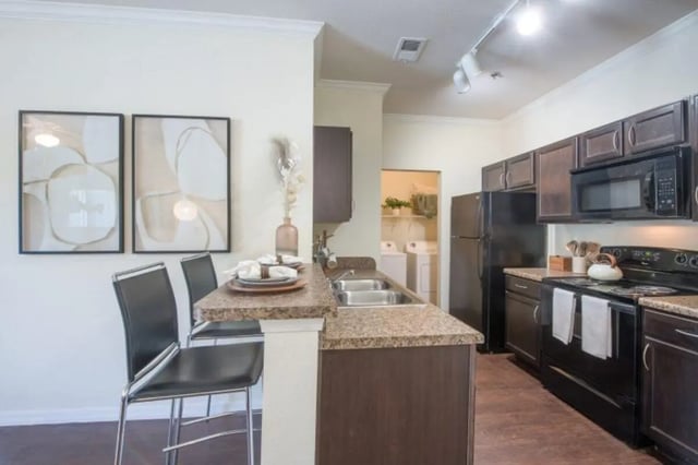 Bar with chairs sink and cabinets kitchen at The Hudson in Albany Student Accommodation