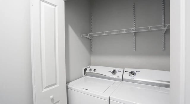 Two white washers and shelves laundry room at Lancaster Apartments in Champaign Student Accommodation