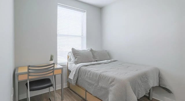 Bed desk plant and chair bedroom at Lancaster Apartments in Champaign Student Accommodation