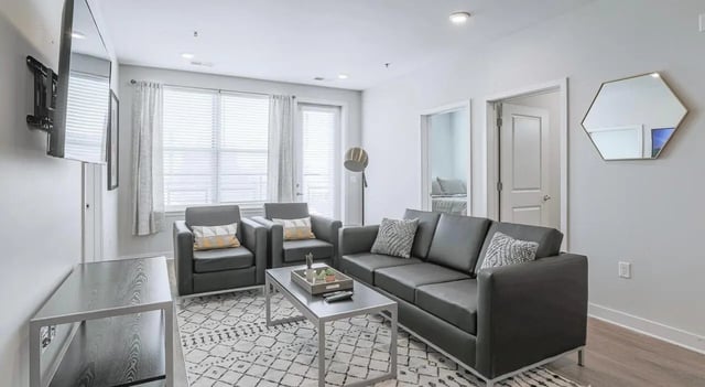 Modern living room with dark sofas hexagonal mirror living room at Lancaster Apartments in Champaign Student Accommodation