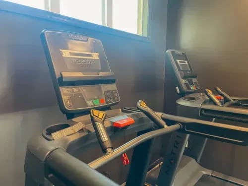 Two treadmills with digital displays gym area at The Towns at Octiv Row in Carrollton Student Accommodation