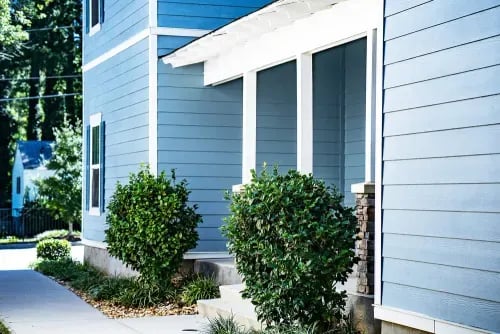 Blue house exterior with porch and bushes exterior at The Towns at Octiv Row in Carrollton Student Accommodation