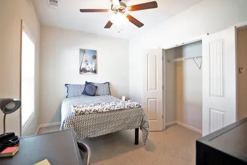 Bed with patterned bedding, open closet, desk bedroom at The Towns at Octiv Row in Carrollton Student Accommodation
