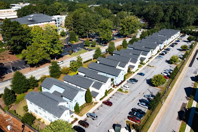 Townhouses with gray roofs and parked cars exterior at The Towns at Octiv Row in Carrollton Student Accommodation