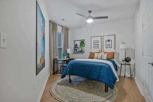 Blue comforter bed desk artwork and ceiling fan bedroom at Mazza GrandMarc in College Park Student Accommodation