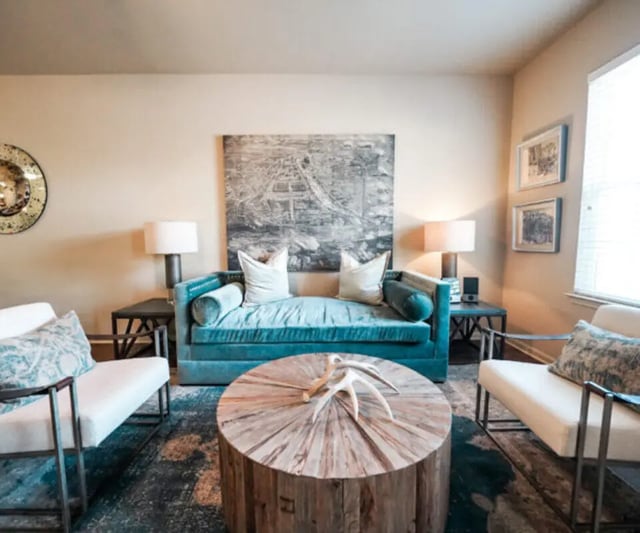 Teal sofa white chairs wood coffee table Living room at The Hamptons Statesboro in Statesboro Student Accommodation