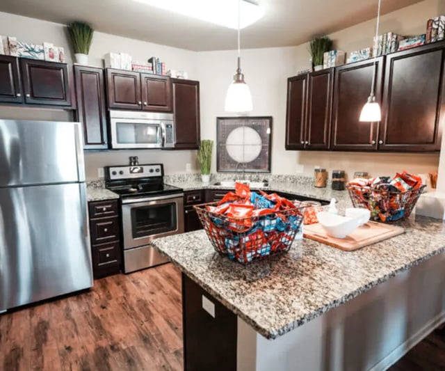Stainless steel refrigerator dark cabinets microwave stove kitchen. at The Hamptons Statesboro in Statesboro Student Accommodation