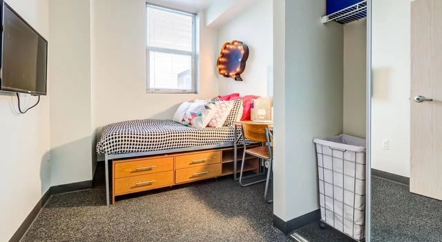 Bed desk television laundry hamper bedroom at Landmark Apartments in Ann Arbor Student Accommodation