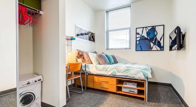 Bed desk closet washing machine bedroom at Landmark Apartments in Ann Arbor Student Accommodation