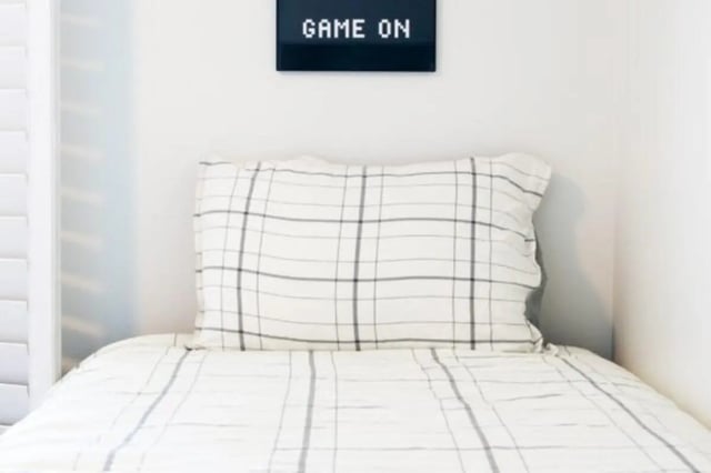 Plaid bedding white wall sign game on bedroom at Nauvoo House Apartments in Rexburg Student Accommodation