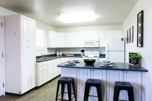 White cabinets island stools and appliances kitchen at Nauvoo House Apartments in Rexburg Student Accommodation