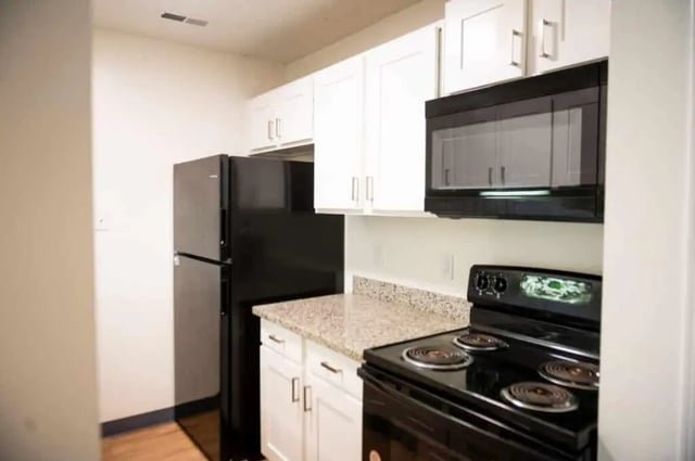 Black refrigerator white cabinets granite countertop stove kitchen at Silvertree Communities in Muncie Student Accommodation