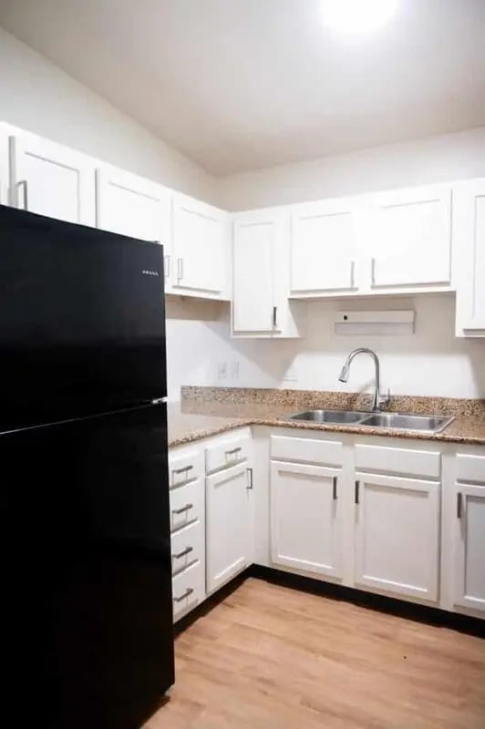 Black refrigerator white cabinets granite countertops sink kitchen at Silvertree Communities in Muncie Student Accommodation