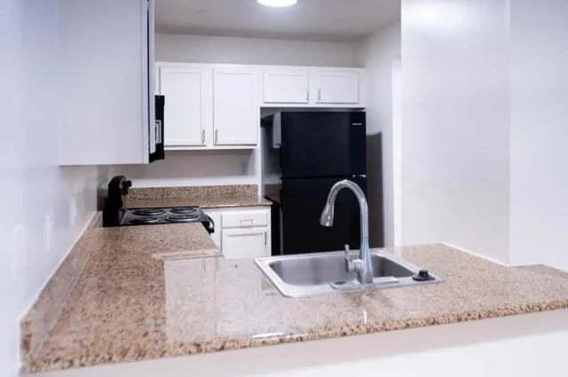 Kitchen with sink stove and black refrigerator kitchen at Silvertree Communities in Muncie Student Accommodation