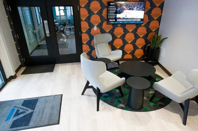 Modern seating area with patterned wallpaper and TV. at The Gates in East Lansing Student Accommodation