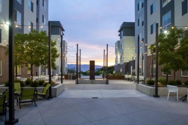 Courtyard with seating tables trees and lights exterior at The Green on Campus Drive in Orem Student Accommodation