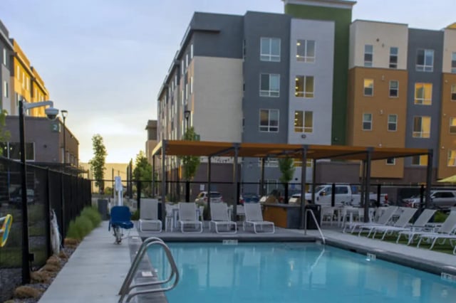 Modern apartment buildings with pool lounge chairs exterior at The Green on Campus Drive in Orem Student Accommodation