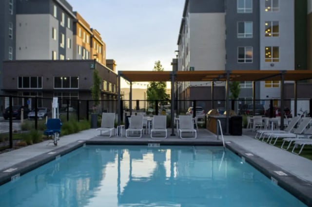 Pool with lounge chairs and buildings exterior at The Green on Campus Drive - Building 4 in Orem Student Accommodation
