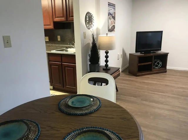 Table chairs kitchen cabinet TV living room at Park Place Apartments in Provo Student Accommodation