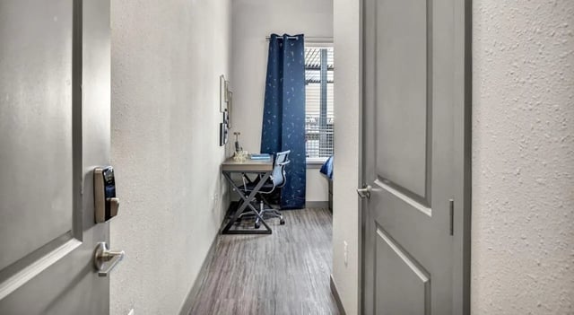 Desk chair and window with blue curtains study area at Haven At Elgin in Houston Student Accommodation