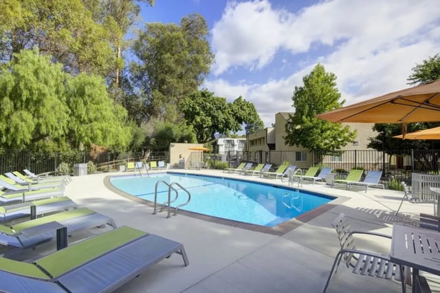 Pool with lounge chairs and umbrellas exterior at Mustang Village Apartments in San Luis Obispo Student Accommodation