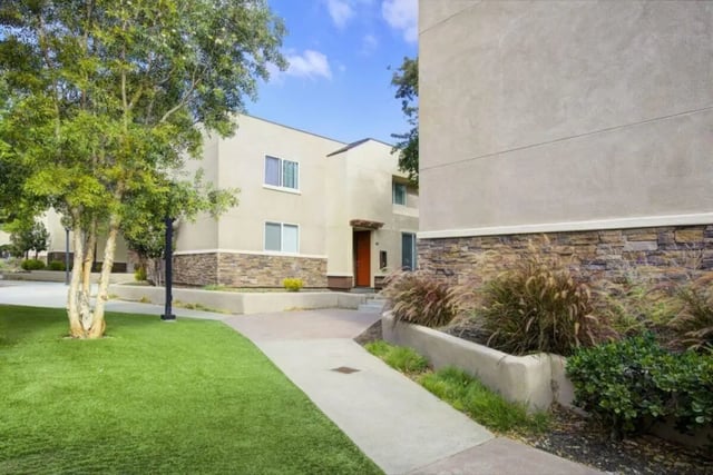 Modern buildings stone accents lawn and walkway exterior at Mustang Village Apartments in San Luis Obispo Student Accommodation