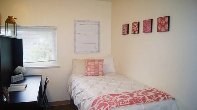 Bed with pink accents desk with book bedroom Image at Mustang Village Apartments in San Luis Obispo Student Accommodation