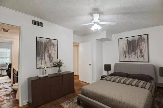 Bed with dresser artwork and ceiling fan bedroom at Starlite Apartments in Denton Student Accommodation