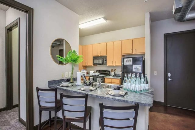 Countertop with chairs, sink, and bottles kitchen at 4050 Lofts in Tampa Student Accommodation
