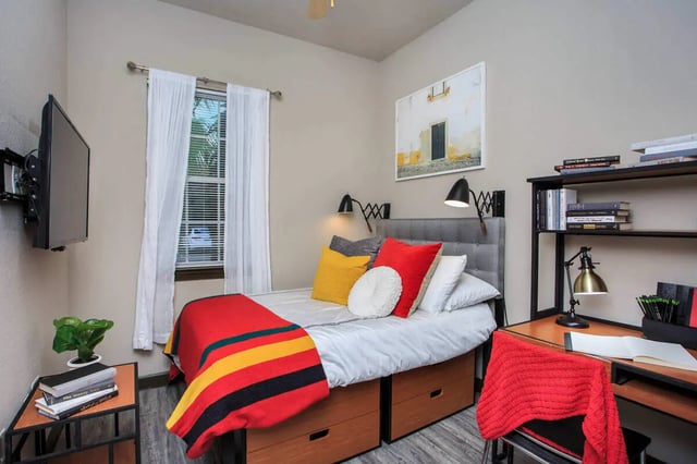 Bed with colorful blanket desk and TV bedroom at 4050 Lofts in Tampa Student Accommodation