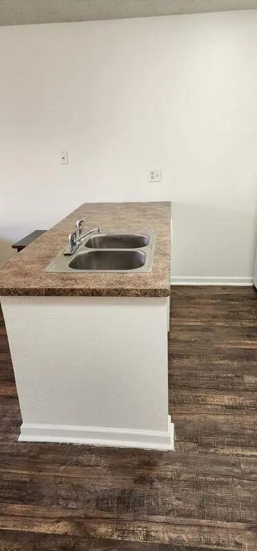 Double sink island countertop dark wood floor kitchen at Baylor Plaza III in Waco Student Accommodation