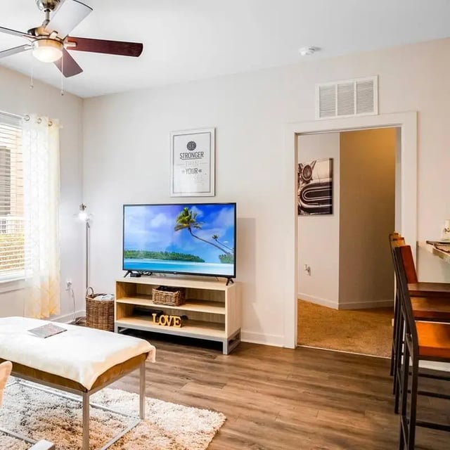 Television on stand with decor and white bench living room at Halo 46 Apartments in Tampa Student Accommodation