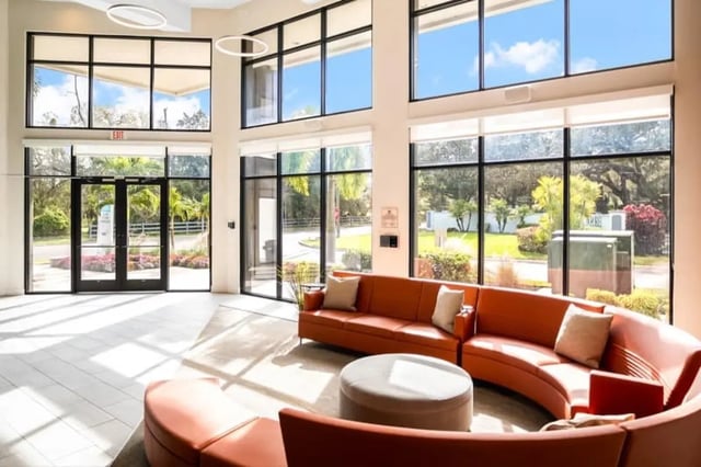 Orange curved sofa round ottoman large windows living room at Halo 46 Apartments in Tampa Student Accommodation