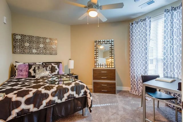 Bed with patterned bedding mirrored dresser desk bedroom at Park Place Baton Rouge in Baton Rouge Student Accommodation