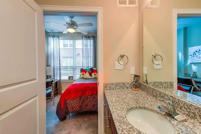 Bed with red cover and colorful pillows bathroom vanity bedroom and bathroom at Park Place Baton Rouge in Baton Rouge Student Accommodation