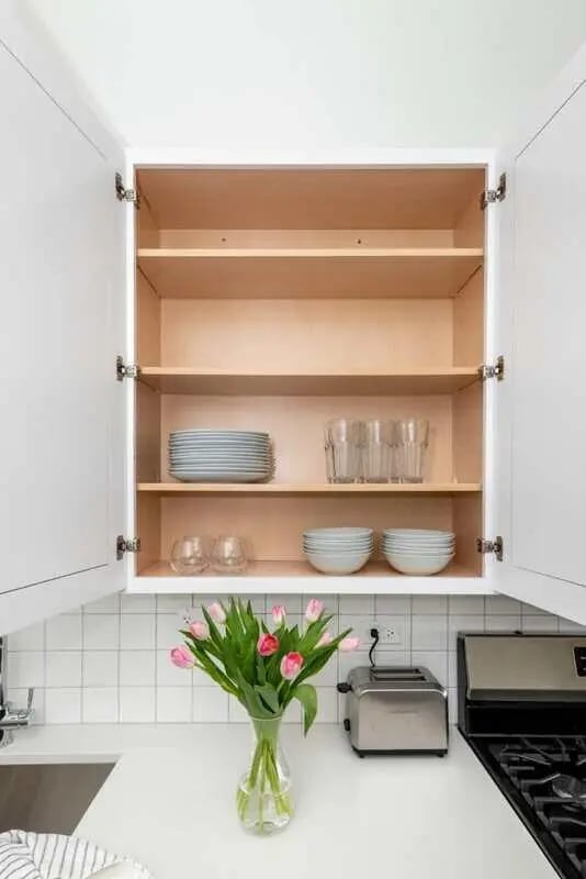 Open cabinet with plates glasses bowls kitchen at Addams Coliving in Chicago Student Accommodation