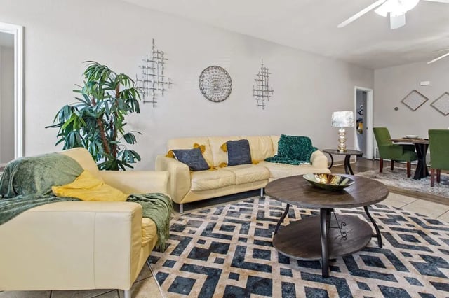 Cream sectional sofa blue pillows green throw living room at Bear Crossing Apartments in Waco Student Accommodation