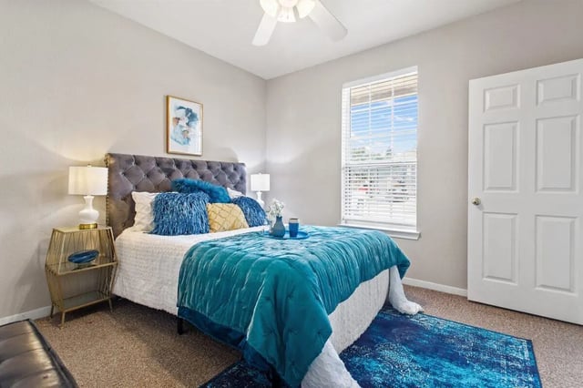 Tufted headboard bed teal bedding blue rug bedroom at Bear Crossing Apartments in Waco Student Accommodation