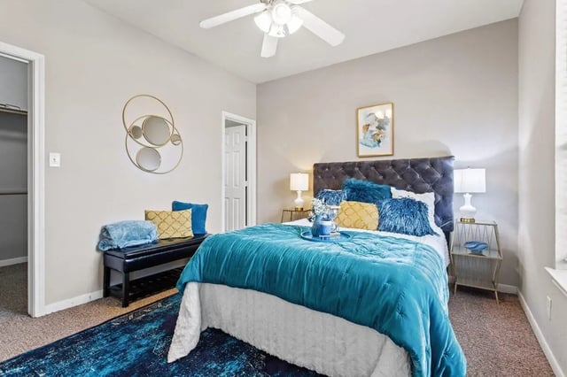 Tufted headboard teal bed bench mirrors Bedroom at Bear Crossing Apartments in Waco Student Accommodation