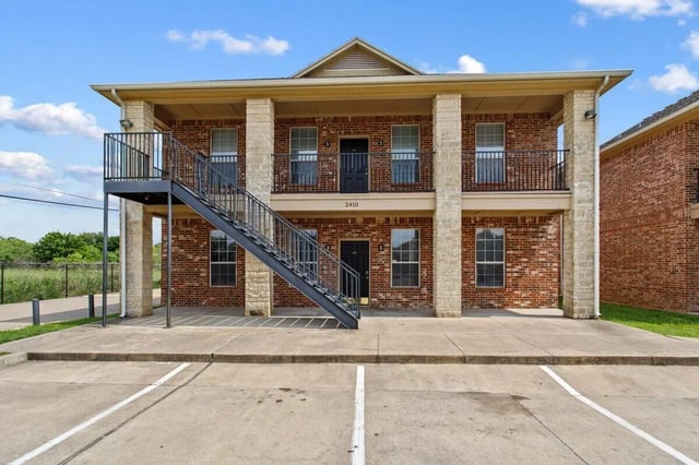 Brick building with balconies and stairs exterior at Bear Crossing Apartments in Waco Student Accommodation