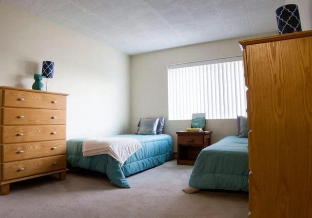 Two beds dresser nightstand and window bedroom at Collegiate Arms in State College Student Accommodation
