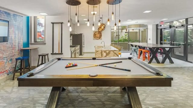 Pool table billiard cues kitchen area and dining table common area at Varsity on K Apartments in Washington Student Accommodation