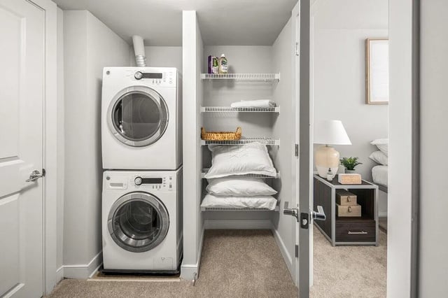 Stacked washer dryer and storage shelves with bedding Image Type Laundry Room at Varsity on K Apartments in Washington Student Accommodation