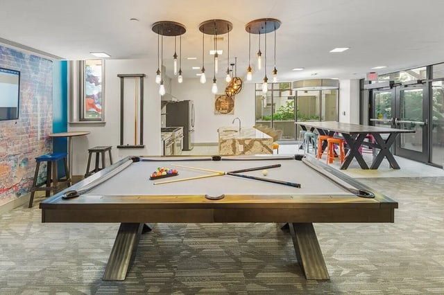 Pool table with balls cues and stools game room at Varsity on K Apartments in Washington Student Accommodation