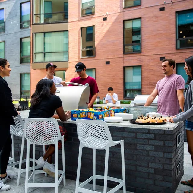 Students grilling food and socializing outdoors communal area at 505 on Walnut Apartments in Syracuse Student Accommodation